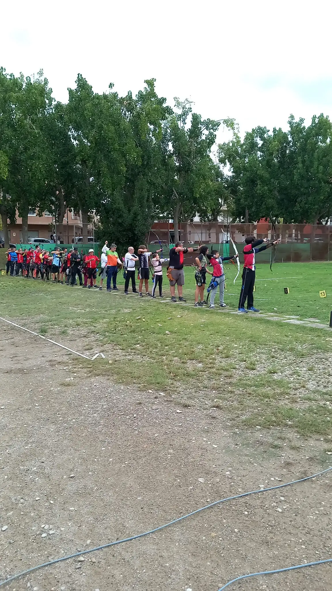 arqueros tirando en la linea de tiro del campo de tiro con dianas al fondo