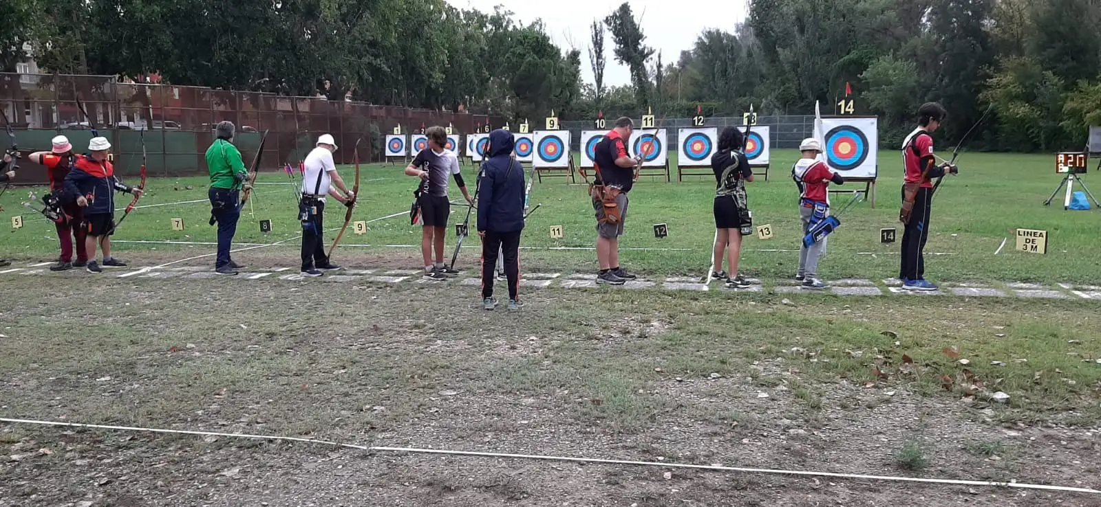 arqueros tirando en la linea de tiro del campo de tiro con dianas al fondo