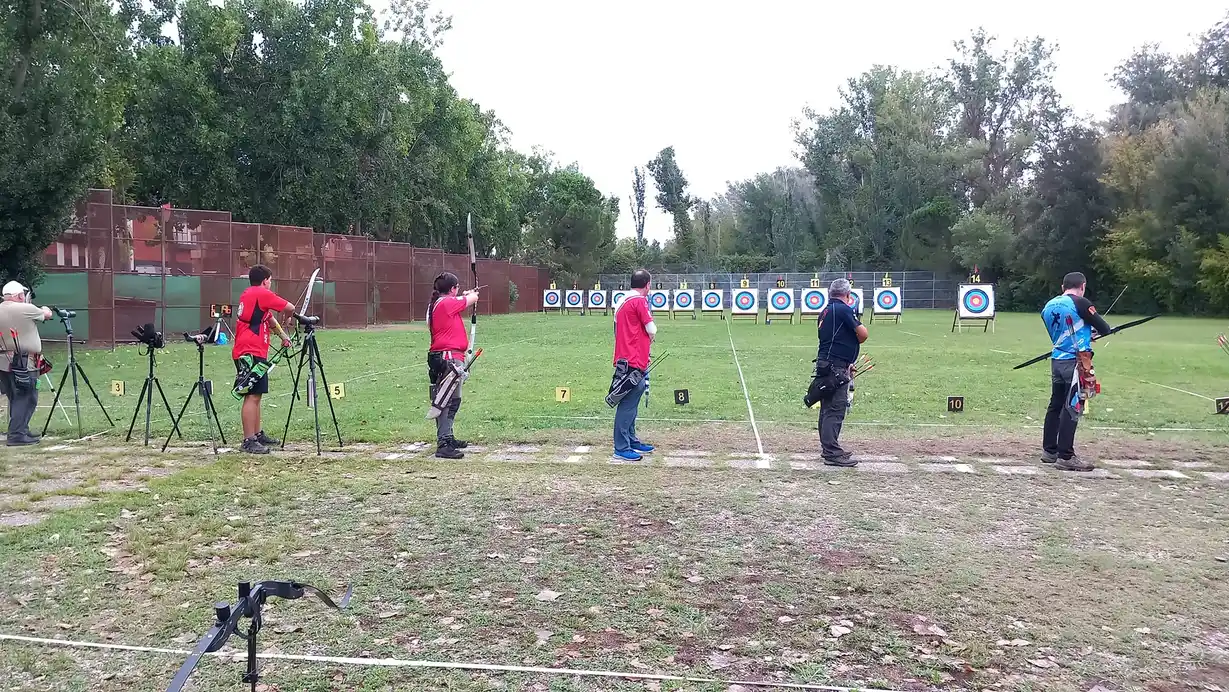 arqueros tirando en la linea de tiro del campo de tiro con dianas al fondo