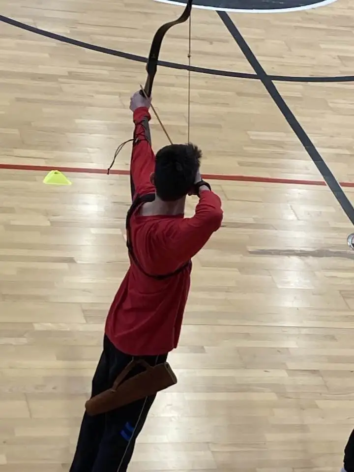 arquero joven tirando con longbow en sala