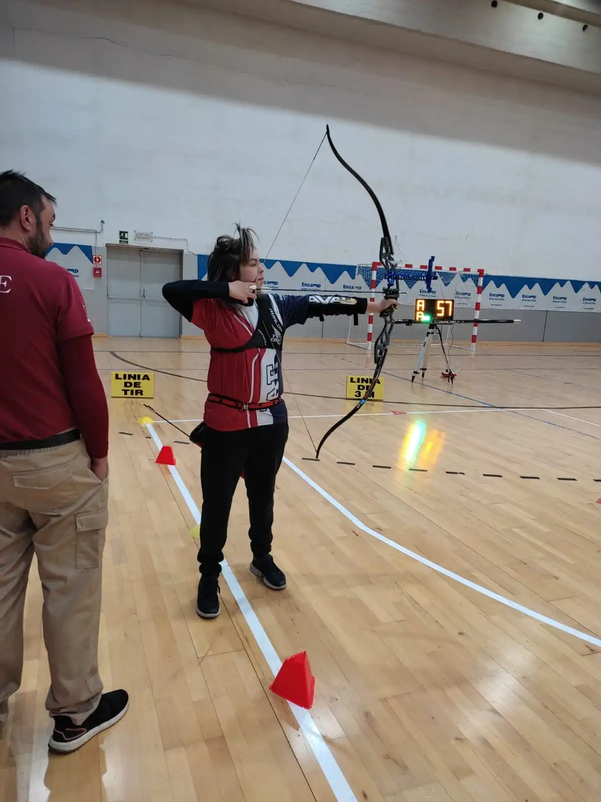 arquero joven tirando con arco recurvo con juez mirando